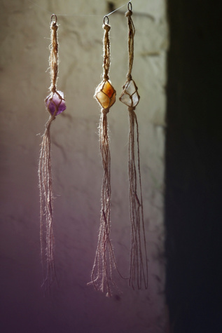 Image: three small crystals hanging in raffia macrame.